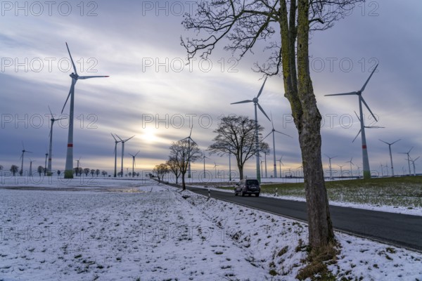 Country road, wind farm, north of Lichtenau, self-proclaimed energy town, over 190 wind turbines and over 1200 solar panels generate 10 times as much electricity as the community of 11, 900 inhabitants consumes, largest onshore cluster of wind turbines in Germany, winter, slightly snowy landscape, North Rhine-Westphalia, Germany, Europe