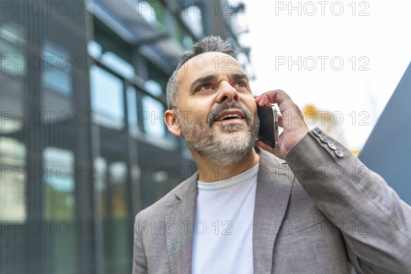 Confident mature businessman talking to the mobile outdoors in the financial district