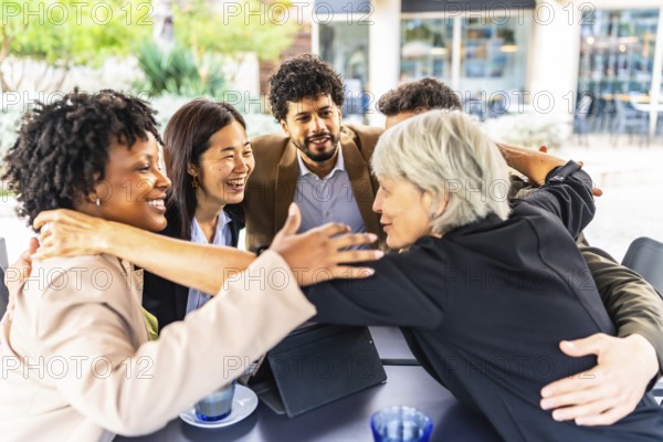 Business team of multi-ethnic people embracing together in circle standing in a cafeteria