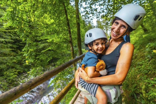 Mother holding her son while wearing helmets and enjoying the breathtaking scenery of vintgar gorge in bled, slovenia