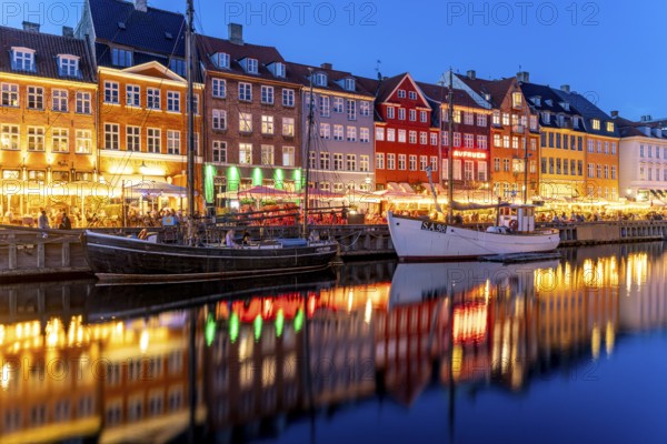 Colourful houses, restaurants and historic ships on the Nyhavn canal and harbour at dusk, Copenhagen, Denmark, Europe