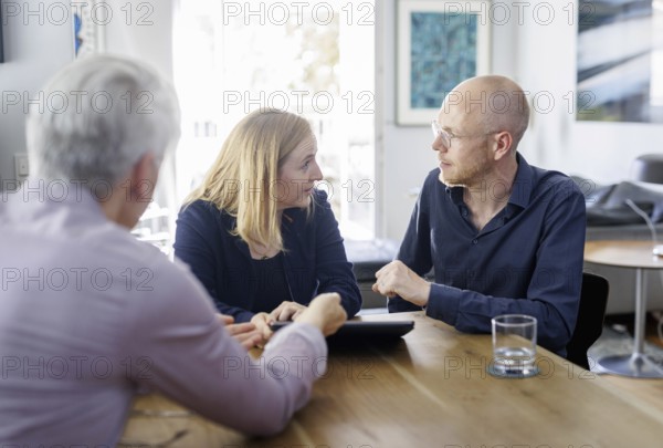 Symbolic photo on the subject of counselling. A young woman and a young man sit together at a table at home and receive counselling. Berlin, 13.08.2024