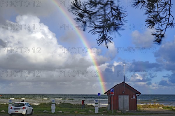 Beach landscape with rainbow and clouds over the sea and scattered green trees, car park, Tönsberg, Oslofjord, Norway, Europe