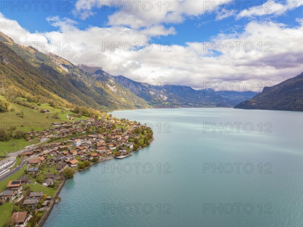 Village on the shore of a large lake, surrounded by mountains and clouds, panoramic style, Lake Brienz. Switzerland