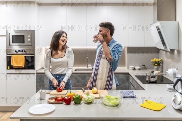 Happy couple preparing a healthy meal of fresh vegetables in their kitchen, enjoying time together and sharing a laugh