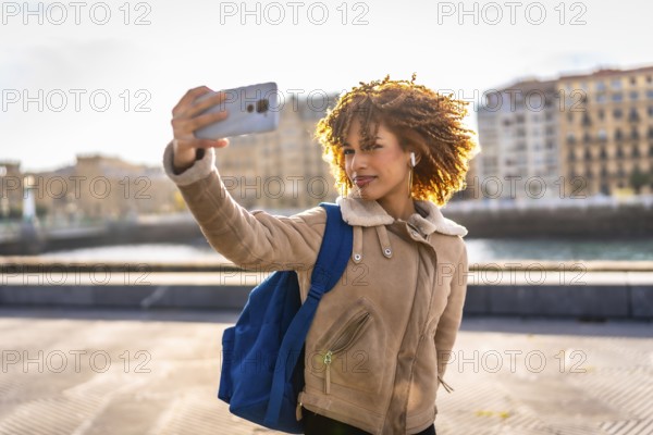 Beauty latin young woman taking selfie with smartphone enjoying sunset in the city