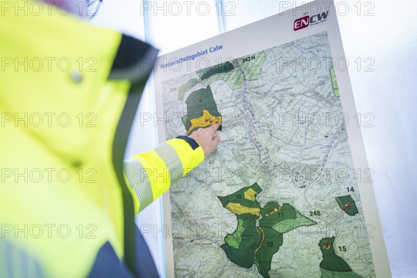 Person pointing to a map of a water protection area, highlighted zones in yellow and green, ENCW Netze Calw waterworks, Calw, Black Forest, Germany, Europe