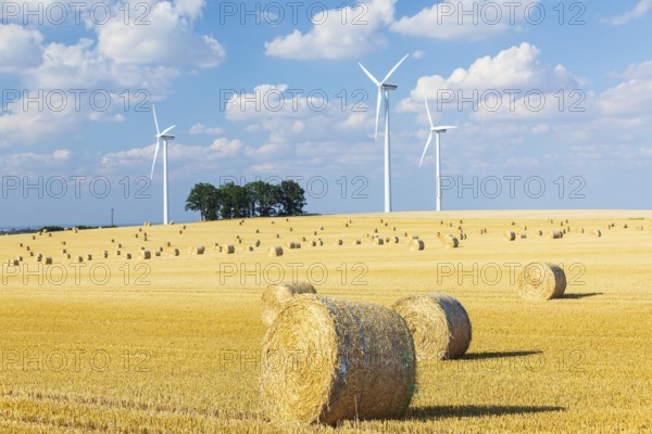 Straw bales on a harvested grain field, stubble field, wind turbines in the background, Nossen, Saxony, Germany, Europe