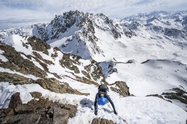 Mountaineer climbing up a steep snow slope, secured by a rope, ascent to the summit of Piz Grialetsch in winter, view of mountain panorama with Piz Vadret with snow, Grisons Haute Route, Albula Alps, Rhaetian Alps, Grisons, Switzerland, Europe
