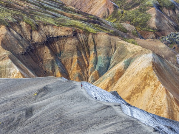 Hikers decending the slopes of Mt. Blahnukur, colorful rhyolite mountains, lava field, Landmannalaugar, Fjallabak Nature Reserve, Iceland, Europe