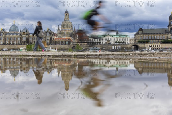 The Dresden silhouette with a cyclist and dark clouds behind the Church of Our Lady is reflected in a puddle on the Elbe cycle path, Elbe cycle path, Dresden, Saxony, Germany, Europe