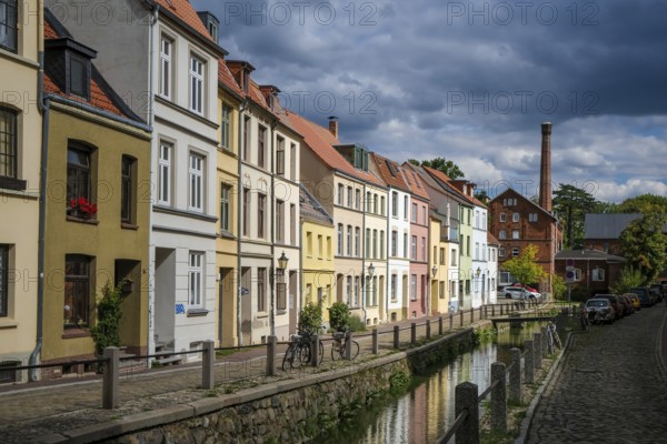 Wismar, Mecklenburg-Western Pomerania, Germany, renovated old town of the Hanseatic city of Wismar, restored colourful eaves houses at the mill pit, historic canal, streets with cobblestones, old town is an area monument of urban architecture, Unesco, world cultural heritage, in the back the old town mill, Europe
