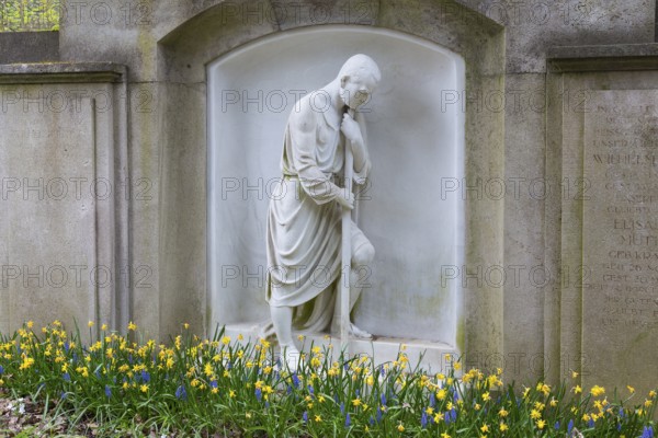 Grave with large figure of a man and spring blossom, Dresden Forest Cemetery, Saxony, Germany, Europe