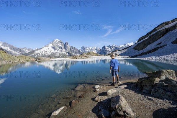 Mountaineer in front of mountain landscape with mountain lake, tourist at Lac Blanc with water reflection, mountain peak Aiguille Verte, Grandes Jorasses, Aiguille du Moine and Mont Blanc, Mont Blanc massif, Chamonix-Mont-Blanc, Haute-Savoie, France, Europe