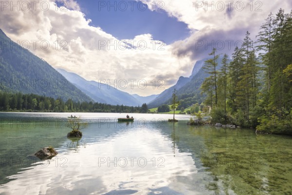 Hintersee with rocks and trees in the foreground, surrounded by mountains after sunset with dramatic cloudy sky, rowing boats, Ramsau, Berchtesgaden National Park, Berchtesgadener Land, Upper Bavaria, Bavaria, Germany, Europe