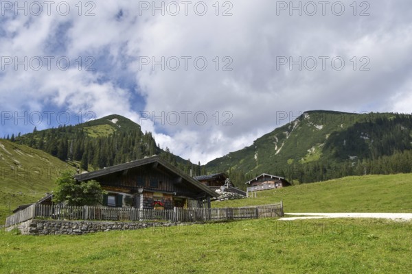 The rustic alpine huts on the Hochalm, with Reifelberg on the left and Sonntagshorn on the right, the highest mountain in the Chiemgau Alps, Salzburger Land, Austria, Europe