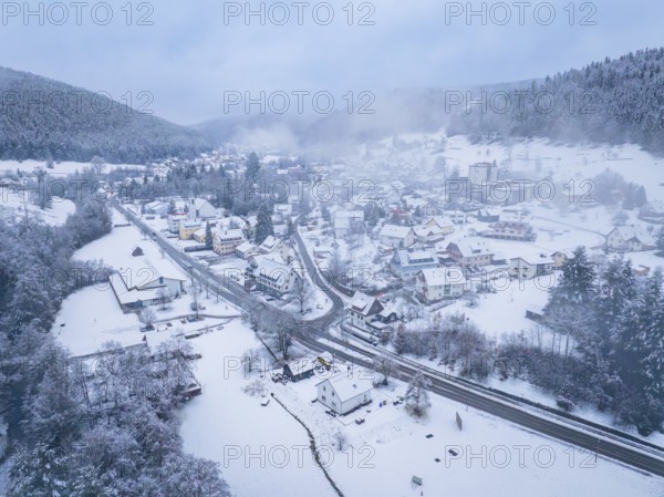 Foggy village in the mountains with snow-covered houses and streets. A peaceful winter panorama, Enzklösterle, district of Calw, Black Forest, Germany, Europe