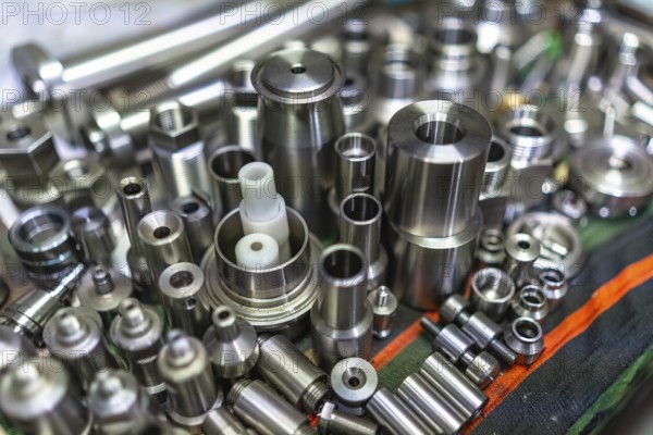 Close- up of a raw of small finished metal pieces placed on surface in metallurgic factory