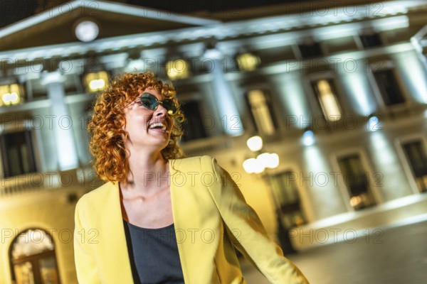 Woman with curly hair and sunglasses enjoying nightlife at city