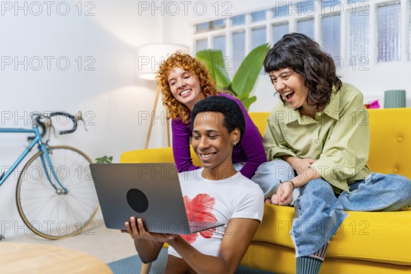 Lgtb multi-ethnic flatmates using laptop sitting on the sofa