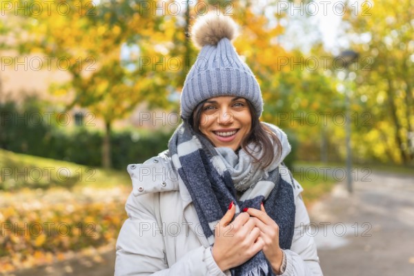 Portrait of a beauty woman wearing warm clothes in a park during a sunny and cold day of autumn