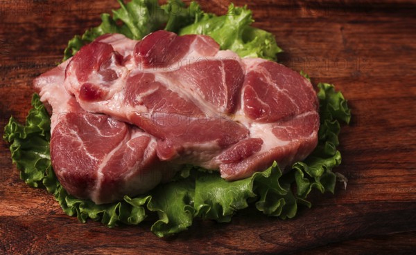 Raw pork steak, two pieces, on a wooden background