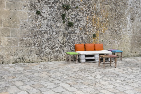 Pallet bench with colourful cushions in front of a high wall, Matera, Basalikata, Italy, Europe