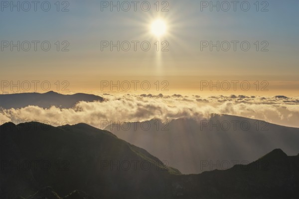 Aerial drone view of mountains over clouds near Pico Ruivo on sunset. Madeira island, Portugal, Europe
