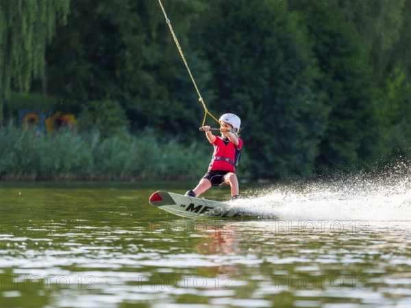Boy or girl with wakeboard in the lake, water sports, water skiing in the wake park