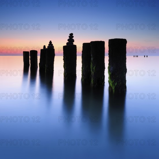 Stone pyramids on old groynes with algae in the water on the beach of the Baltic Sea, long exposure at sunset, Wustrow, Fischland-Darß-Zingst peninsula, Mecklenburg-Vorpommern, Germany, Europe