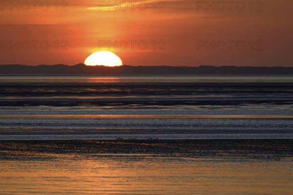 Sunset over the North Sea at low tide, the outline of the island of Juist on the horizon, Norddeich, Lower Saxony, Germany, Europe