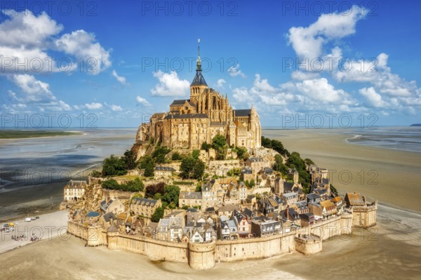 Impressive building complex on an island in a vast sandy landscape under a blue sky, Le Mont-Saint-Michel