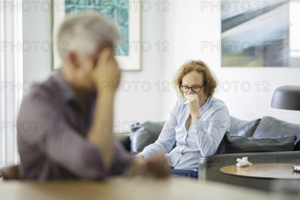 Symbolic photo on the subject of problems in a partnership. An older woman and an older man sitting at home. Berlin, 13.08.2024