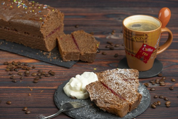 Pieces of chocolate cake with icing sugar, whipped cream and coffee beans lying around