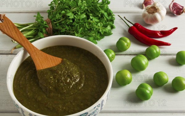 Tkemali sauce, traditional Georgian cuisine, green cherry plum, with ingredients for sauce, cilantro, mint, hot pepper, garlic, on a white wooden table, close-up, rustic, food background, no people, selective focus, sauce, green sauce, tkemali, georgian cuisine, homemade