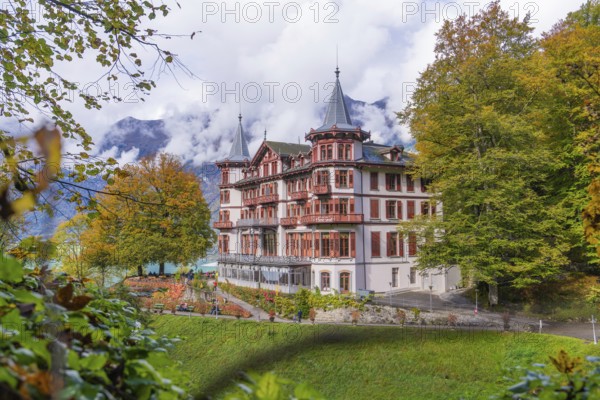 Large hotel against a mountain backdrop in autumnal surroundings with dramatic clouds, Grandhotel Giessbach, Lake Brienz, Switzerland, Europe