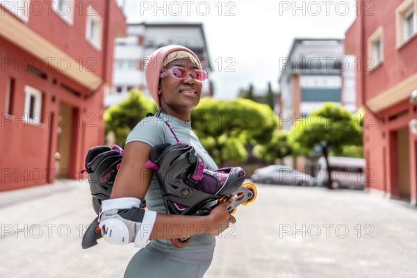 Side view of a modern african girl holding inline skates in the city