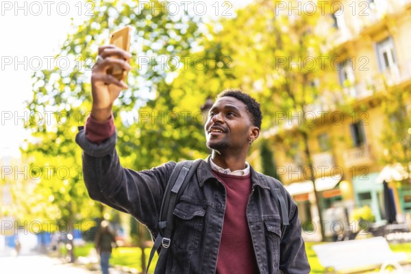 African male young traveler taking photos of a city while walking along the street