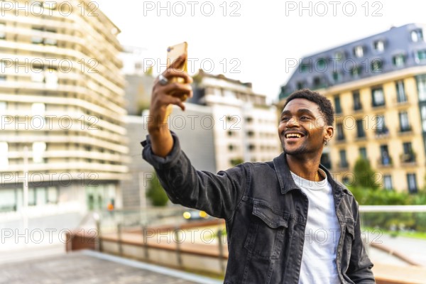 Happy african man taking a selfie smiling at camera standing in the city