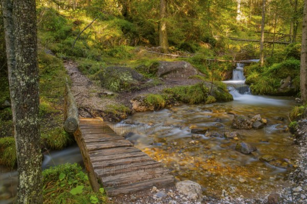 View of a wooden bridge crossing a torrent Fürth with a small waterfall in the background