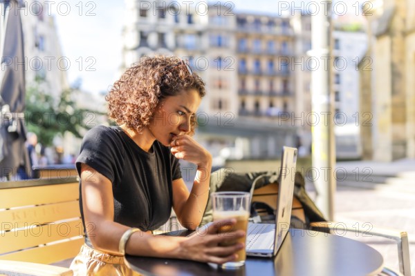 Arab young businesswoman drinking coffee sitting on a terrace working with laptop in the city