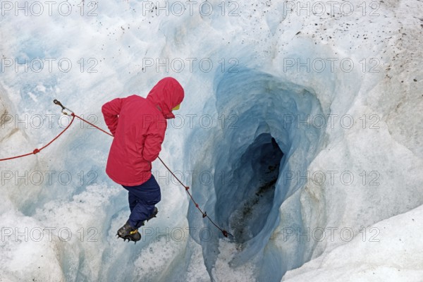 Mountaineer descending into a glacier Ice cave, Fox Glacier, Westland National Park, South Island, New Zealand, Oceania