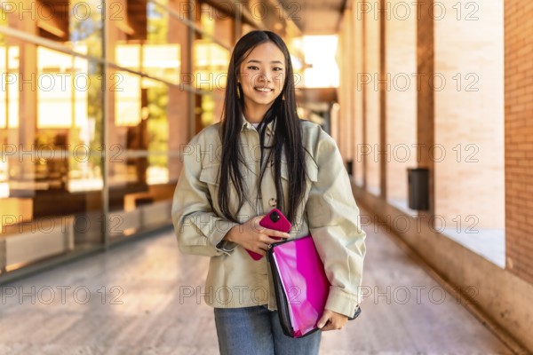 Frontal portrait of a chinese beauty female student standing smiling at camera at the university