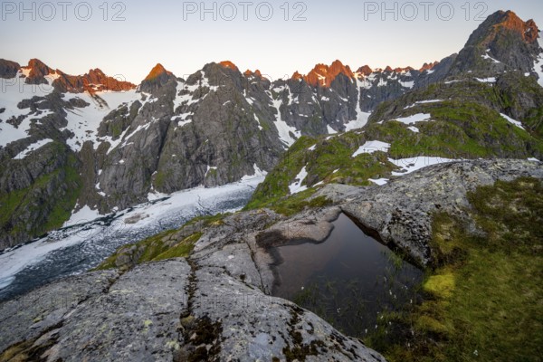 Rocky mountain peaks and Trollfjordvatnet with snow, small pond in moorland at Trollfjord Hytta, mountain landscape with alpenglow at sunrise, at Trollfjord, Lofoten and Vesterålen, Nordland, Norway, Europe