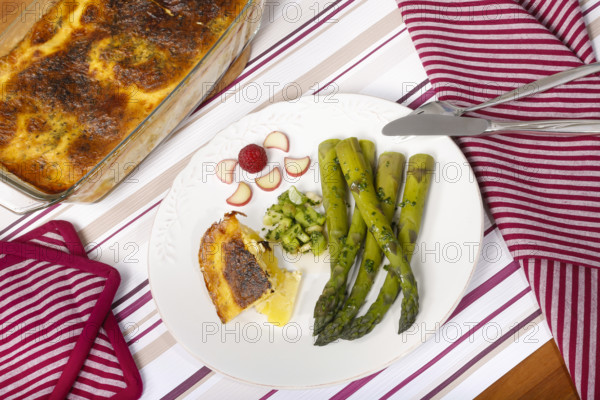 South German cuisine, green asparagus with rhubarb vinaigrette and potato gratin, healthy, vegetables, served on a plate, vegetarian, cutlery, knife, fork, casserole dish with gratin, gratinated, traditional cuisine reinterpreted, food photography, studio, Germany, Europe