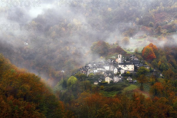 Village view of Corippo in the fog surrounded by autumn-coloured deciduous trees, Verzasca Valley, Canton Ticino, Switzerland, Europe