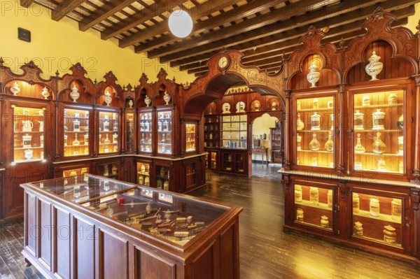 Traditional pharmacy interior with illuminated glass cabinets and woodwork, Jerez