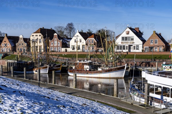 The fishing village of Greetsiel, historic fishing harbour, with the largest shrimp cutter fleet in East Frisia, historic houses, winter, partly frozen, in Lower Saxony, Germany, Europe