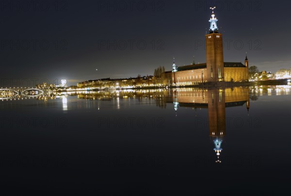 Illuminated building by a calm body of water at night with reflecting water and dark sky, capital city, city hall, Stadshus, Nobel Prize, Stockholm, Sweden, Europe