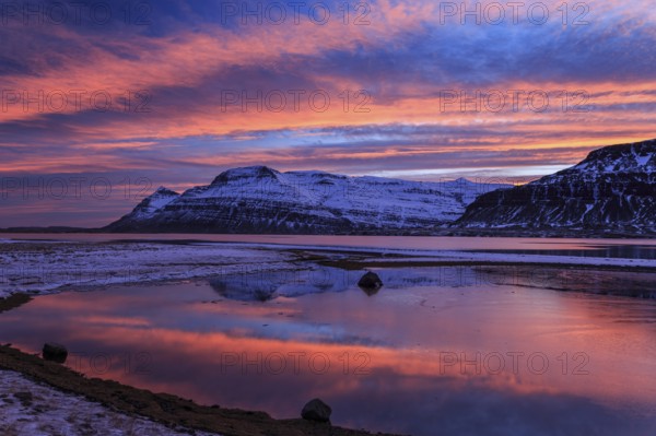 Sunset over a snowy mountain, reflected in a fjord, East Fjords, Iceland, Europe
